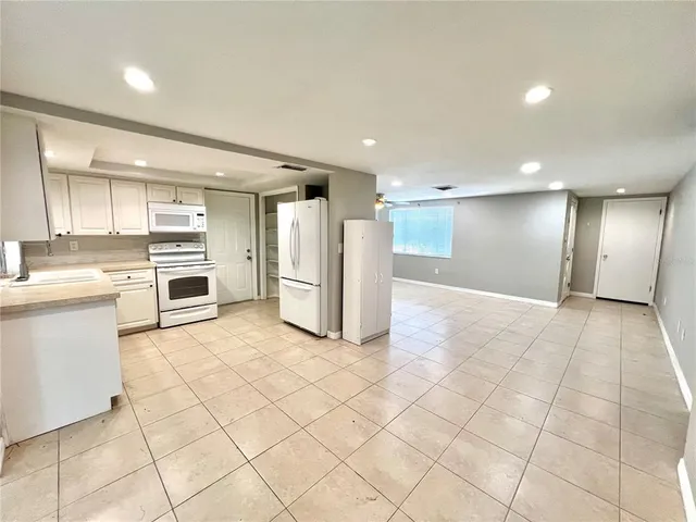 a large white kitchen with white cabinets and a refrigerator