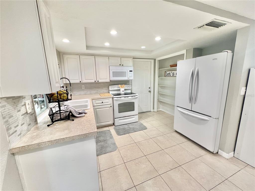 12206 Quail Run Row Hudson, FL 34667 - Photo 9 of 20 a kitchen with a refrigerator a stove and white cabinets
