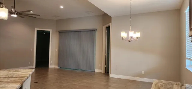 an empty room with kitchen chandelier fan and windows