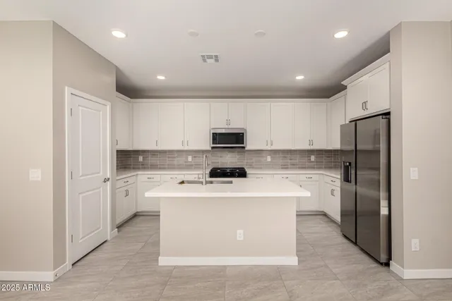 a kitchen with a stove top oven a refrigerator and white cabinets