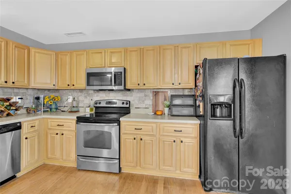 a kitchen with stainless steel appliances granite countertop a refrigerator stove and sink with wooden floor