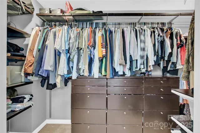 a view of walk in closet with clothes and shoes