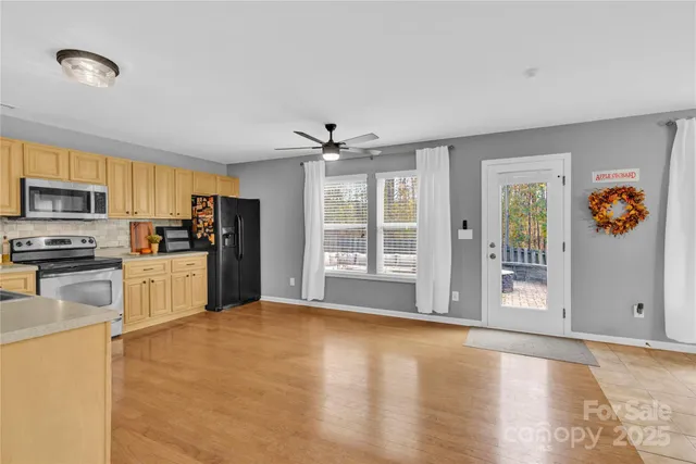 a kitchen with stainless steel appliances granite countertop a refrigerator oven a sink dishwasher and white cabinets with wooden floor