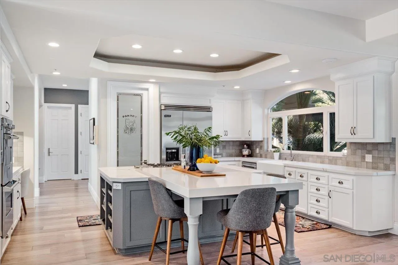 16270 Windpiper Road Poway, CA 92064 - Photo 12 of 65 a kitchen with stainless steel appliances kitchen island granite countertop a dining table chairs and white cabinets