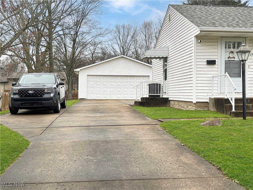 3968 Cannon Road Youngstown, OH 44515 - Photo 2 of 25 View of home's exterior with a garage, a shingled roof, a lawn, and an outbuilding