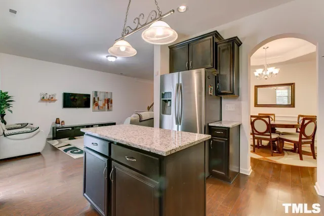 a kitchen with a refrigerator a stove top oven a dining table and chairs with wooden floor