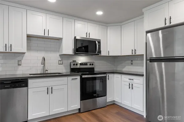 a kitchen with white cabinets stainless steel appliances and a sink