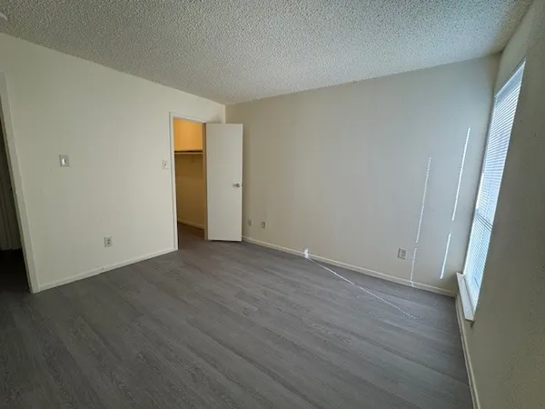 a view of an empty room with wooden floor and closet