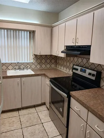 a kitchen with granite countertop a stove sink and cabinets