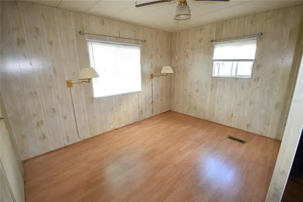 an empty room with wooden floor and windows