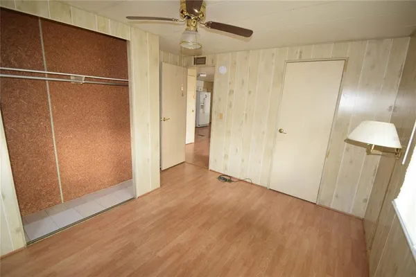 a view of an empty room with wooden floor and a ceiling fan
