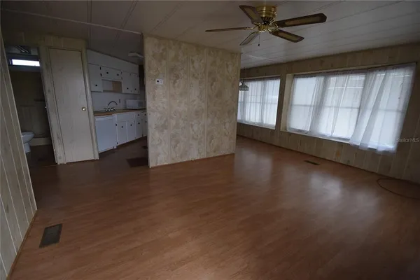 an empty room with wooden floor cabinet and windows