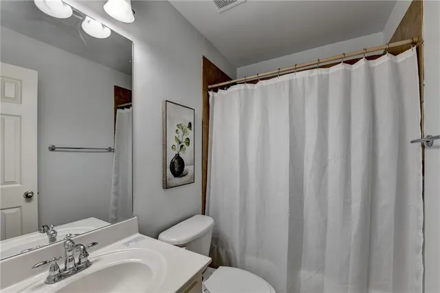 a bathroom with a sink mirror and a toilet