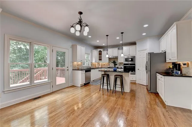 a kitchen with stainless steel appliances granite countertop a refrigerator oven a sink dishwasher a dining table and chairs with wooden floor