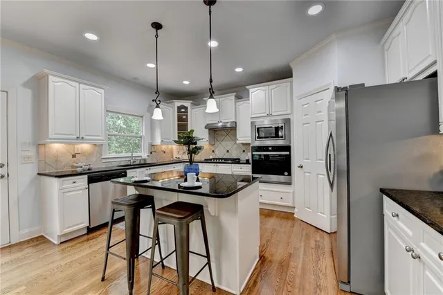 a kitchen with stainless steel appliances granite countertop a stove refrigerator sink and microwave