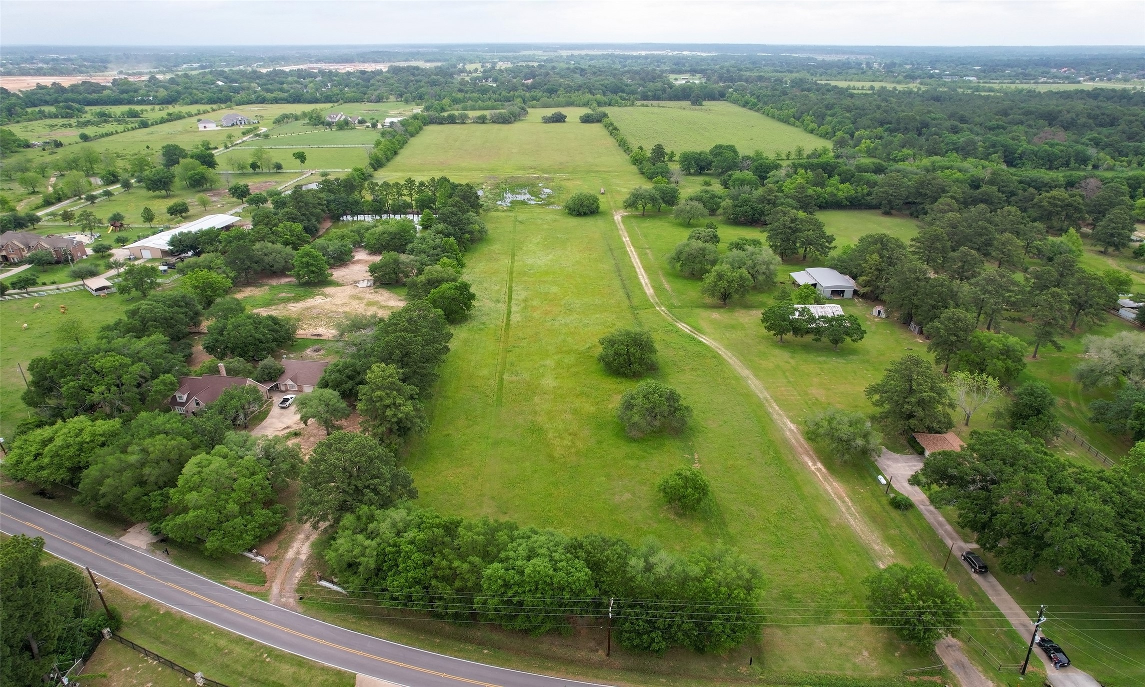 an aerial view of residential houses with outdoor space and trees all around