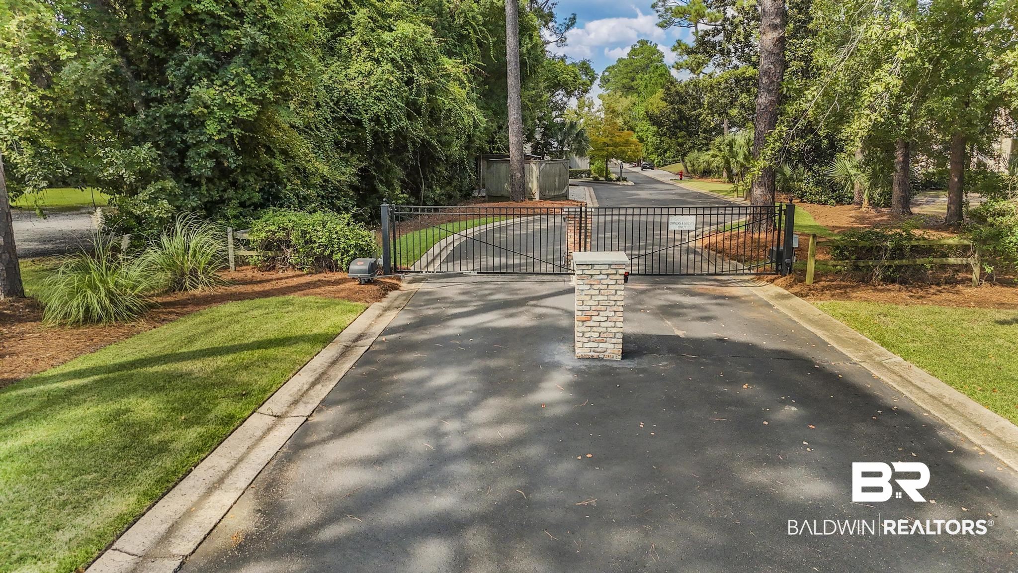 25773 Canal Road Orange Beach, AL 36561 - Photo 6 of 32 Surrounding community featuring a gate, view of scattered trees, and a lawn