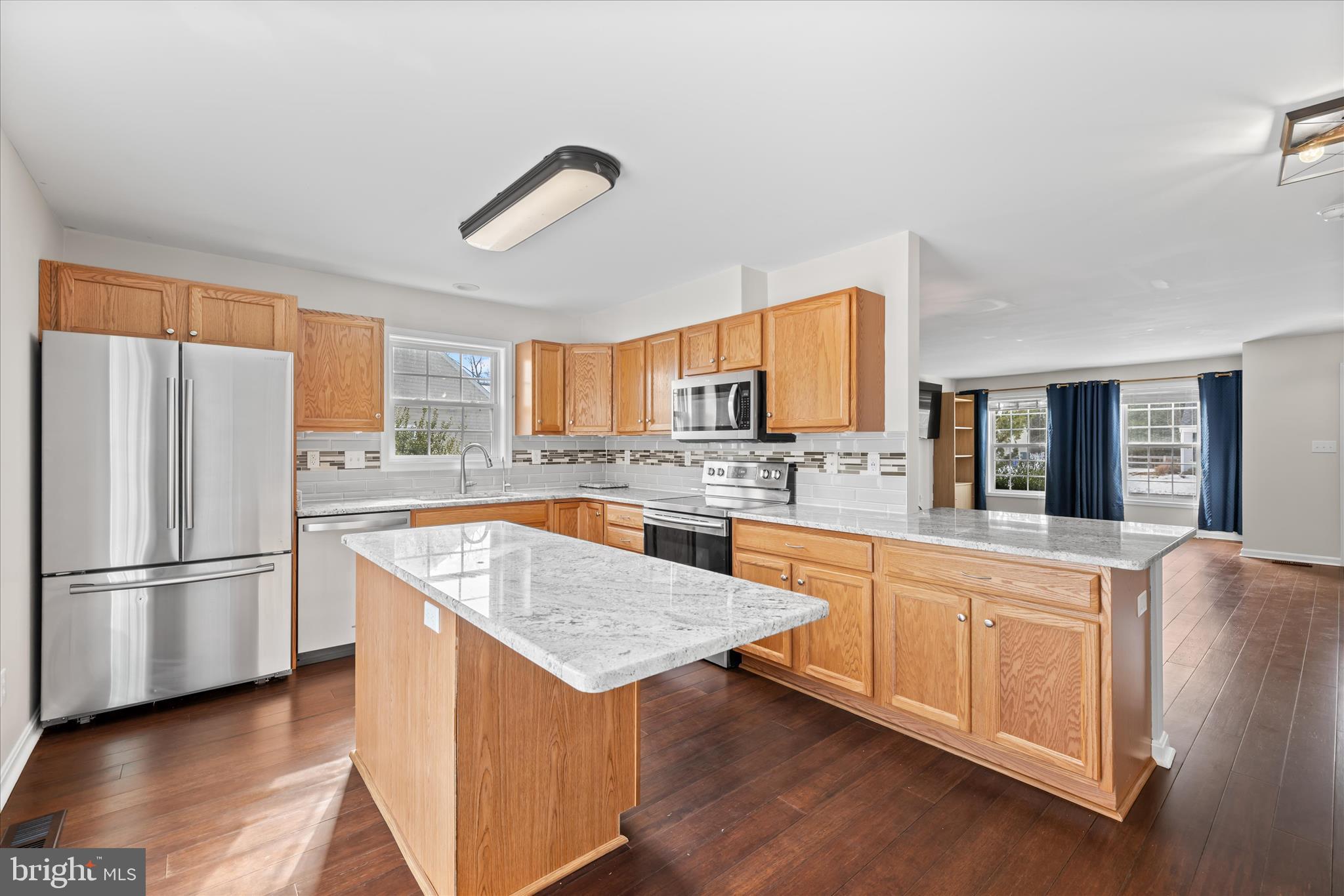 19095 Carey Lane Georgetown, DE 19947 - Photo 9 of 39 a kitchen with stainless steel appliances granite countertop a refrigerator a sink dishwasher a stove with wooden cabinets and wooden floor
