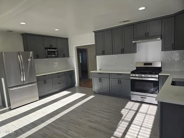 a kitchen with granite countertop a refrigerator and a stove top oven