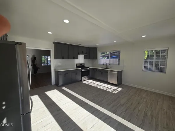a kitchen with stainless steel appliances kitchen island granite countertop a refrigerator oven a sink dishwasher and a stove with wooden floor