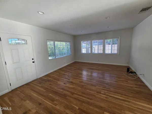 an empty room with wooden floor and windows