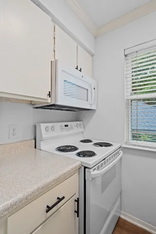 a kitchen with granite countertop white cabinets and white appliances