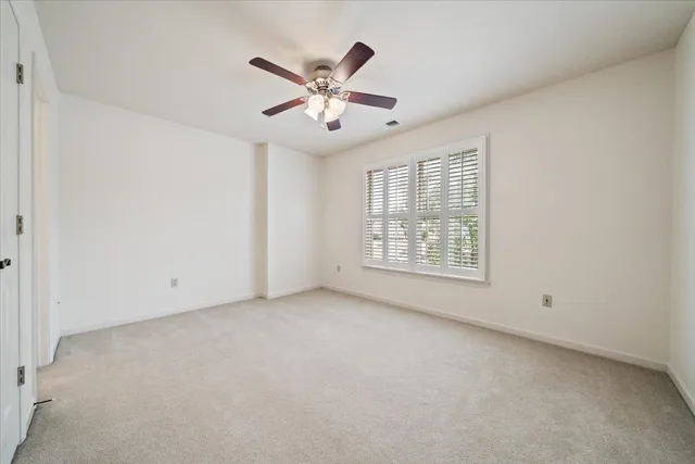an empty room with windows and ceiling fan