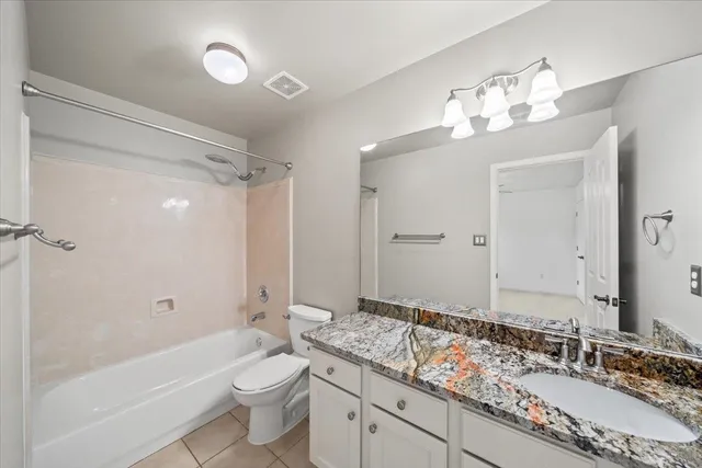 a bathroom with a granite countertop sink a toilet a mirror a bathtub and shower