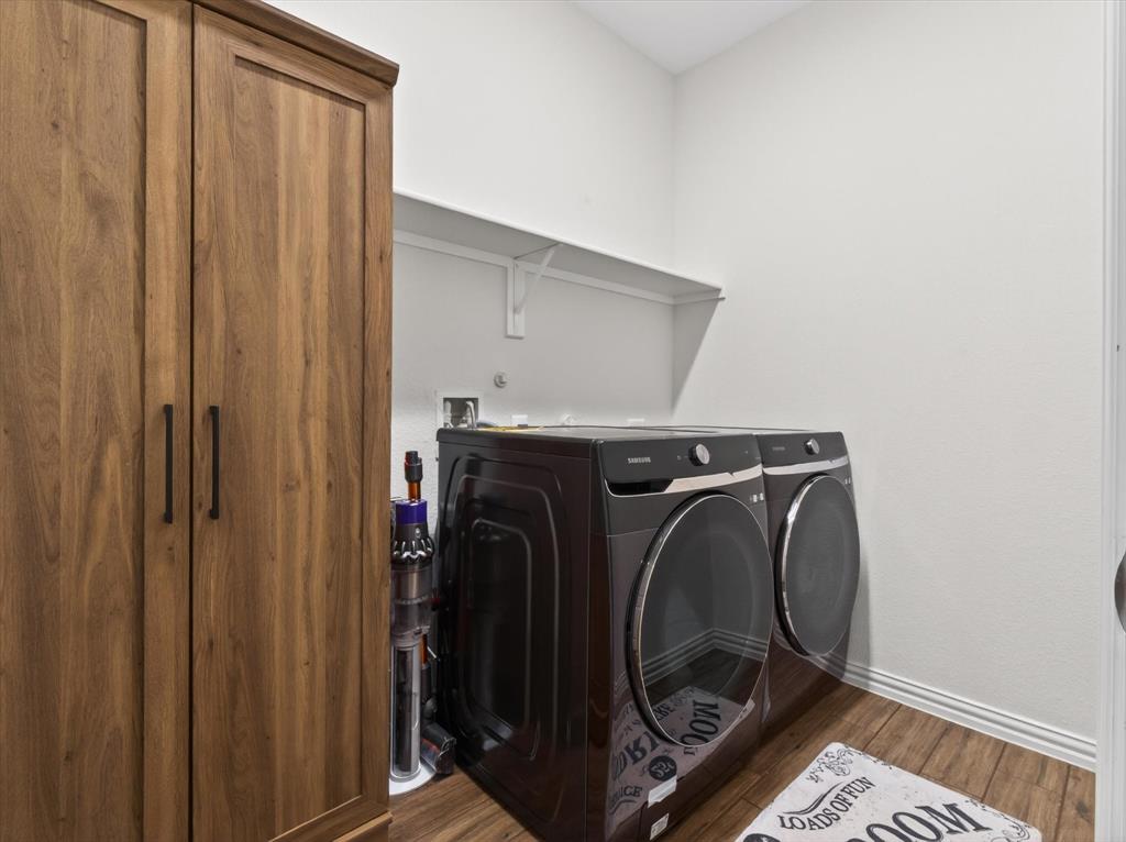 636 Corner Post Path Celina, TX 75009 - Photo 16 of 40 Dedicated laundry area featuring wood-finish flooring, a built-in storage cabinet with dark hardware, and an overhead shelf