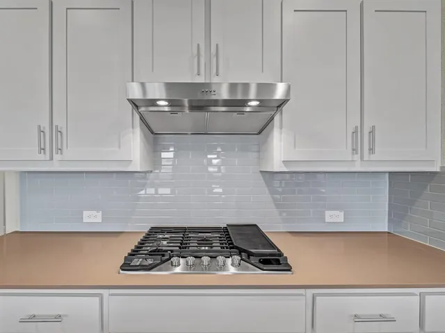 a kitchen with white cabinets and a stove