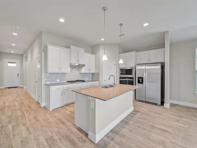 a large kitchen with stainless steel appliances kitchen island a large counter top and a refrigerator