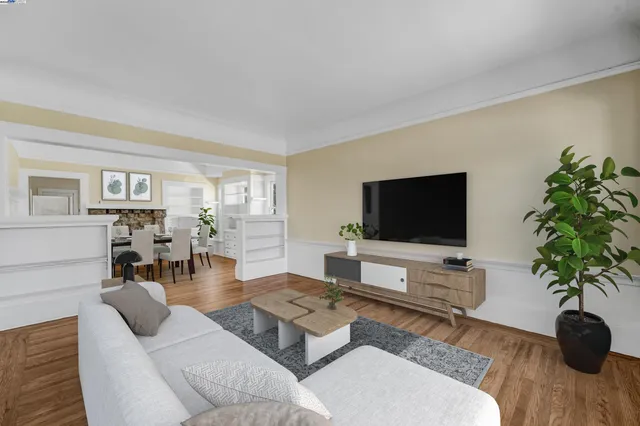 a view of empty room with wooden floor and kitchen view
