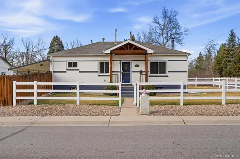 a view of a house with a small yard and large trees