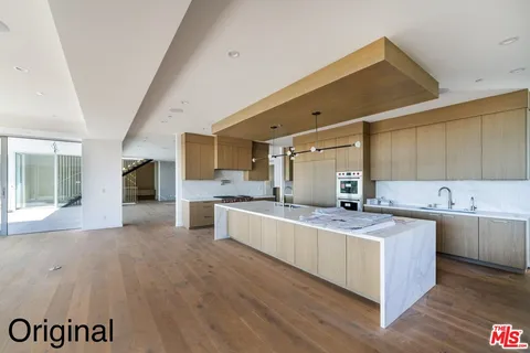 a large kitchen with a lot of counter space and wooden floor