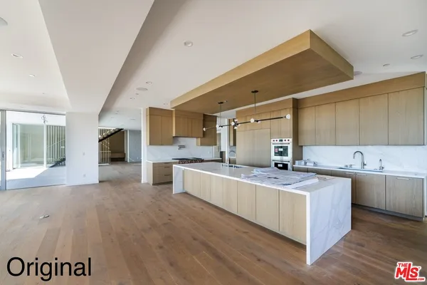 a large kitchen with a lot of counter space and wooden floor