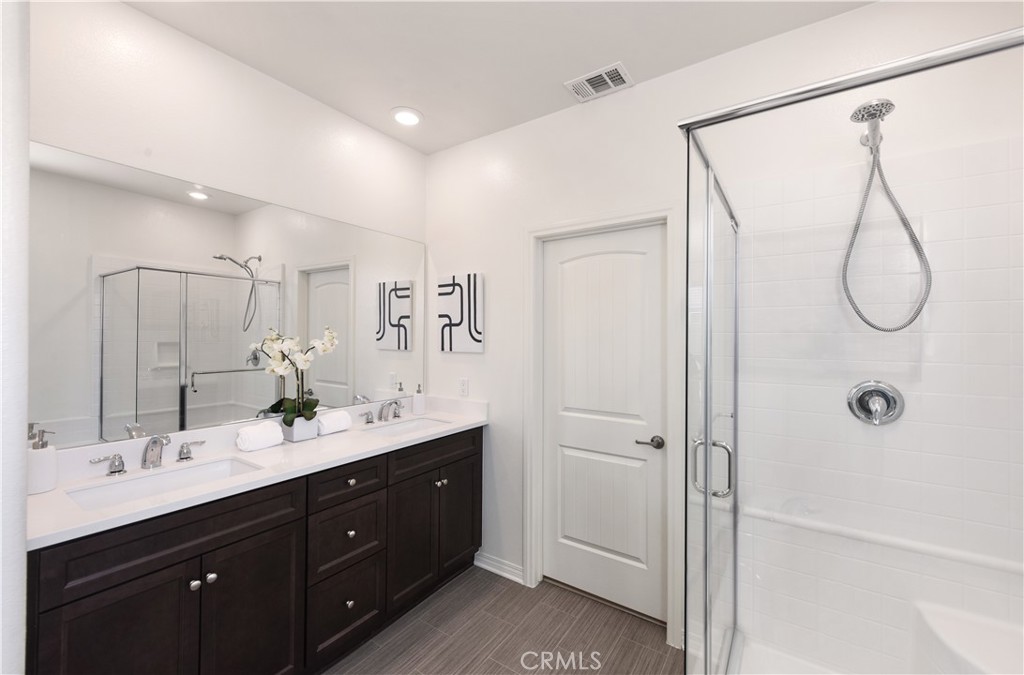 7075 Montecito Lane Eastvale, CA 92880 - Photo 21 of 26 a bathroom with a double vanity sink toilet mirror and shower
