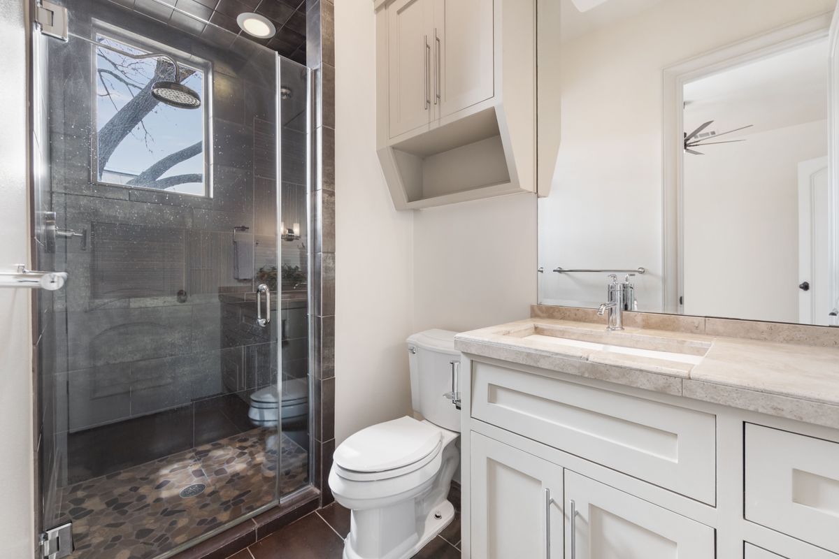 2002 Kinney Avenue, Unit A Austin, TX 78704 - Photo 19 of 26 a bathroom with a granite countertop sink a toilet and a shower