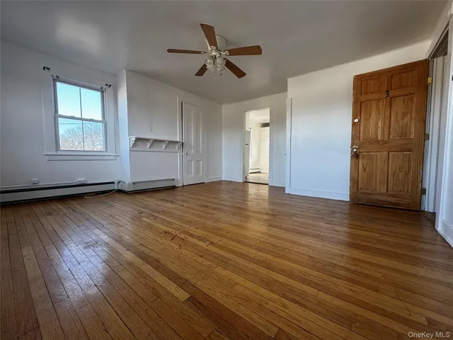 a view of a hallway with wooden floor and a living room