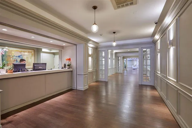 a view of a hallway with wooden floor and a kitchen