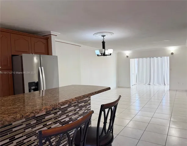 a kitchen with granite countertop a table chairs and refrigerator