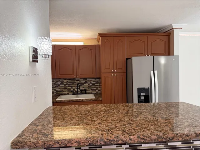 a view of a refrigerator in kitchen and an empty room