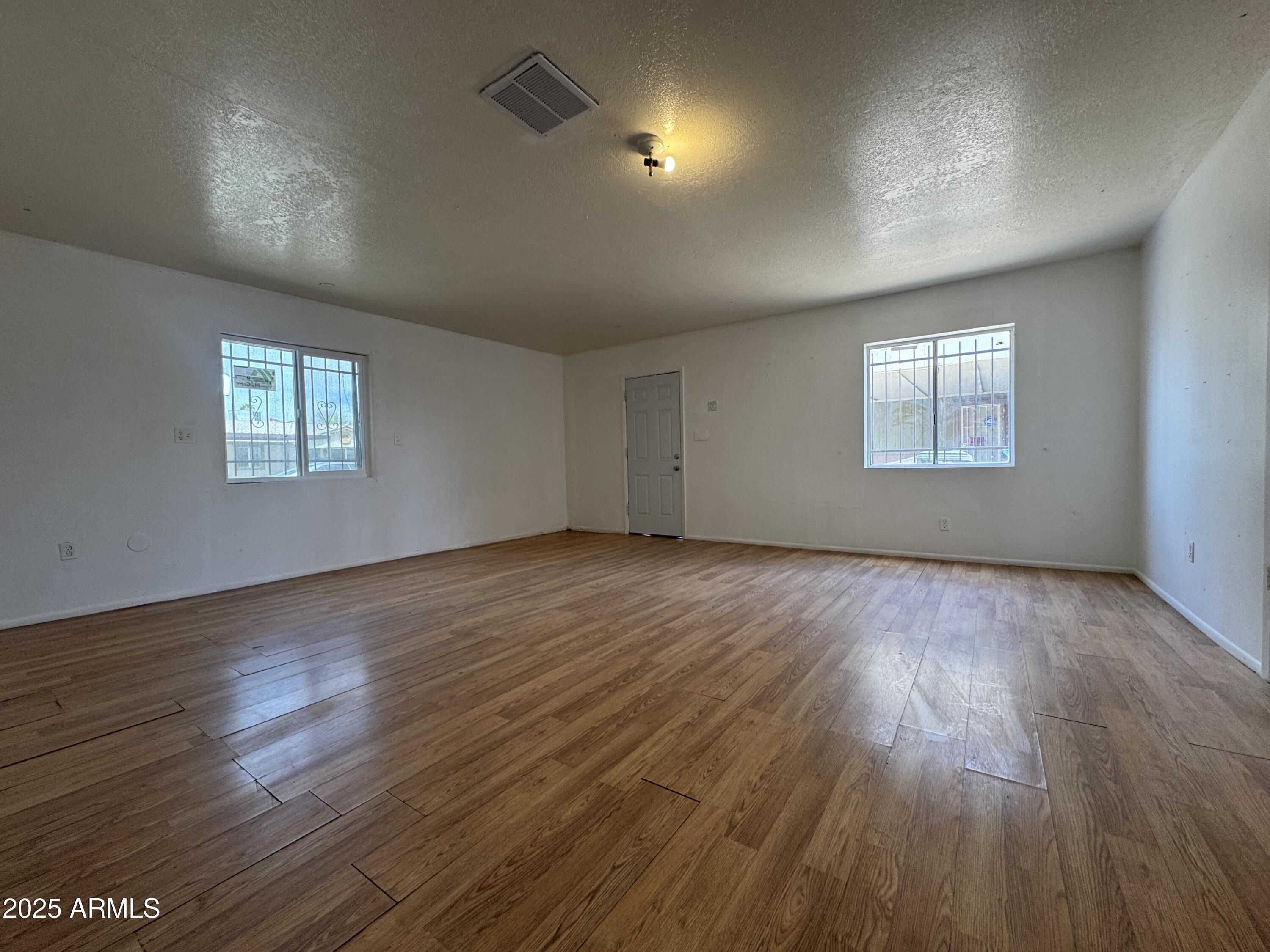 7967 West Highland Avenue Phoenix, AZ 85033 - Photo 15 of 16 an empty room with wooden floor and windows