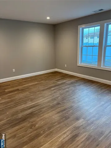 a view of an empty room with wooden floor and windows