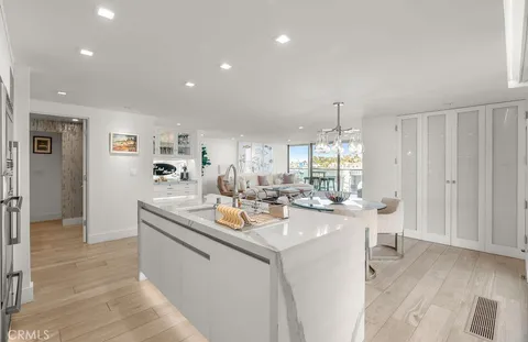 a room with stainless steel appliances kitchen island granite countertop a sink and dishwasher with white cabinets