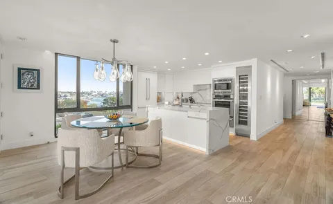 a room with stainless steel appliances kitchen island granite countertop a table chairs and a refrigerator