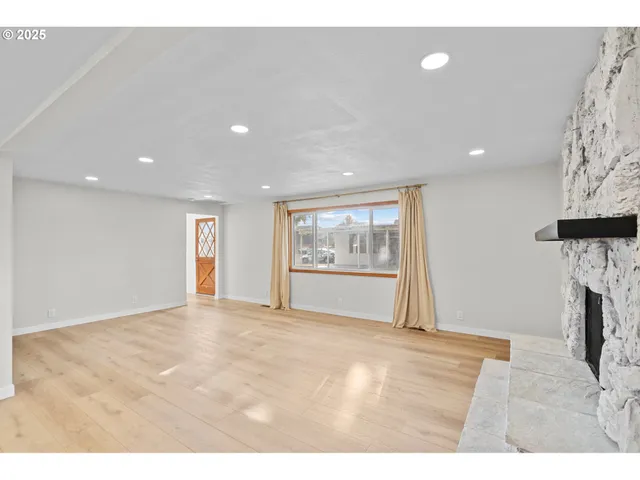 a view of empty room with fireplace and wooden floor
