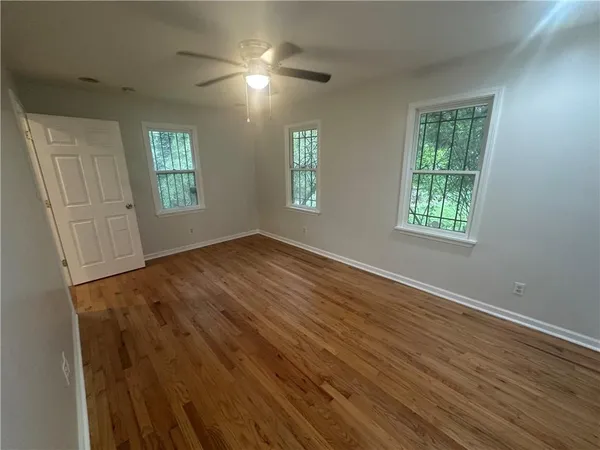 a view of an empty room with wooden floor and a window