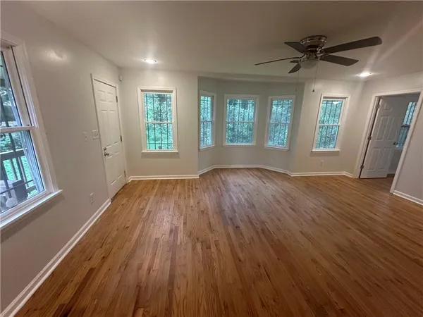an empty room with wooden floor and windows
