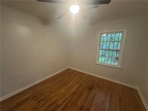 a view of an empty room with wooden floor and a window