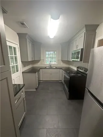 a kitchen with granite countertop stainless steel appliances a sink a counter top space and cabinets